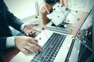 business documents on office table with smart phone and digital tablet and stylus and two colleagues discussing data in the background.jpeg